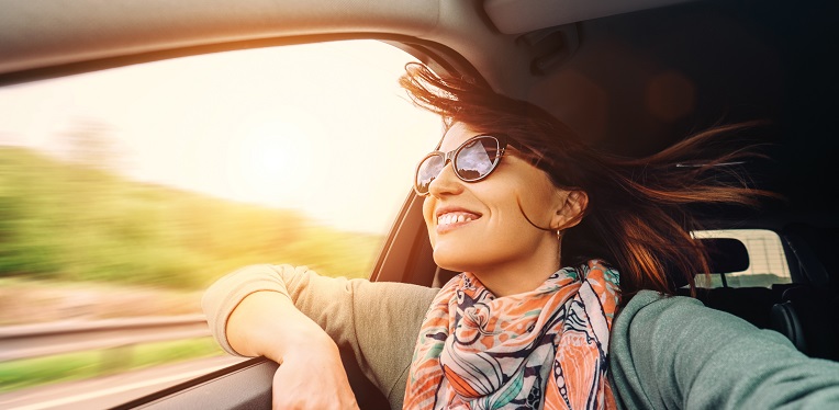 Woman with flying hair looks from car window